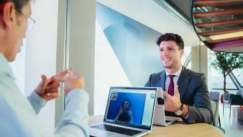 Un cliente de CaixaBank y un gestor hacen uso del servicio de videointerpretaci&oacute;n en lengua de signos SVisual en una oficina. (CaixaBank)