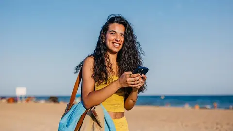 Imagen de una mujer con el m&oacute;vil en la playa. (Telef&oacute;nica)