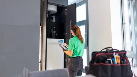 T&eacute;cnico de Iberdrola ante la unidad interior de aerotermia en una vivienda. (Iberdrola)