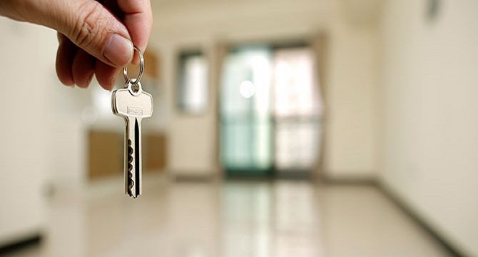 Apartment key in man hand in closeup view as house rental concept