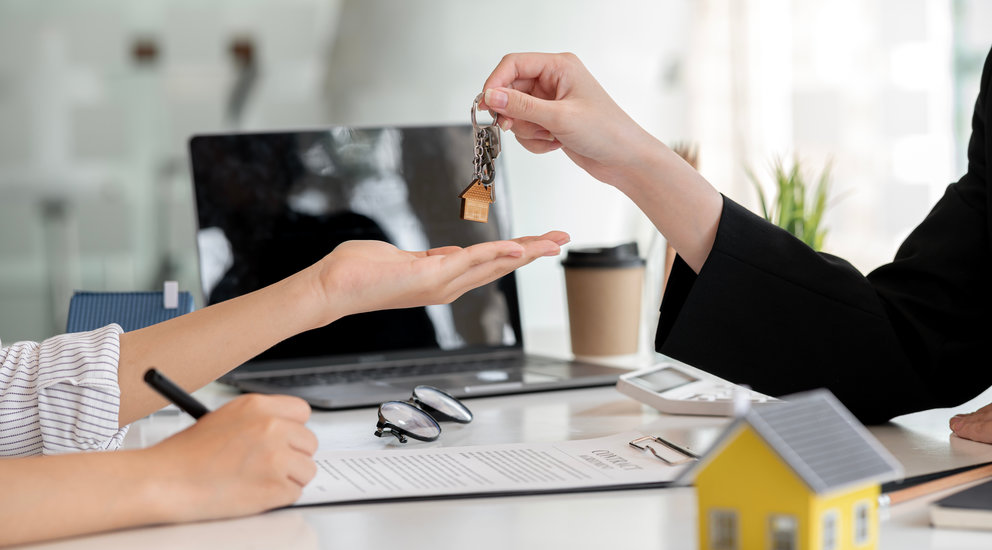 A home rental company agent is handing the house keys to a customer who has agreed to sign a rental contract. Home and real estate rental ideas.