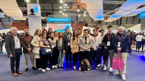 La consejera Carmen Conesa y el director del Instituto de Turismo, con un grupo de estudiantes de Turismo ante el estand de la Regi&oacute;n en Fitur. (CARM)