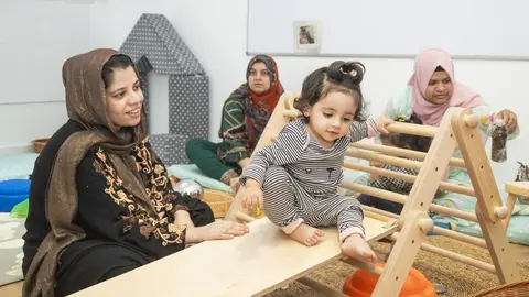 Una madre mira a su hija, subida a un parque de aprendizaje Pikler. (Fundaci&oacute;n 'la Caixa' / Adri&aacute;n Quiroga)