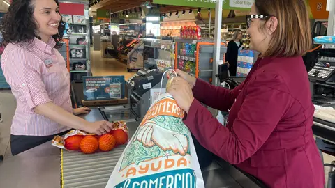 Una mujer compra la bolsa solidaria en favor de los comercios afectados por la DANA en un supermercado Consum. (Consum)