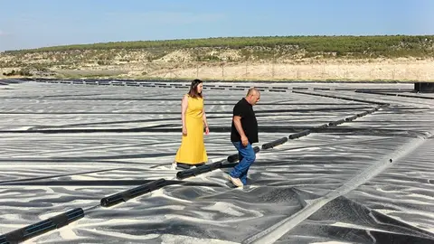 Imagen de la consejera junto a uno de los beneficiarios de las ayudas con las que ha cubierto el embales de agua sobre el que caminan. (CARM)