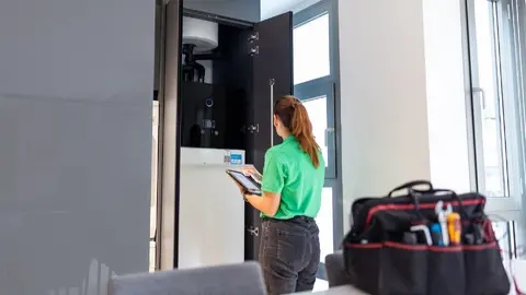 T&eacute;cnico de Iberdrola ante la unidad interior de aerotermia en una vivienda. (Iberdrola)