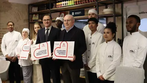 El presidente de Frecom, Jos&eacute; Hern&aacute;ndez, y el subdirector de C&aacute;ritas, Jos&eacute; Antonio Planes, acompa&ntilde;ados por alumnos de la Escuela de Hosteler&iacute;a Eh!. (Frecom)