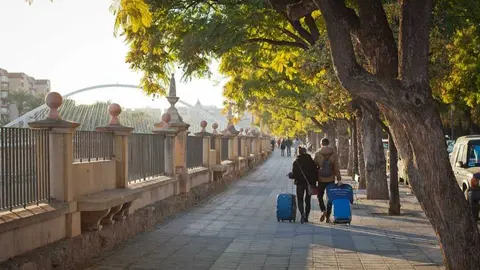 Dos turistas caminando a orillas del Segura con sus maletas. (CARM)