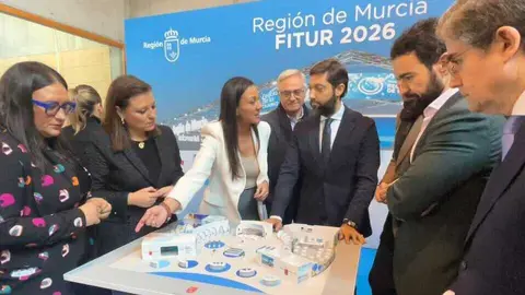 La consejera Carmen Conesa con los directores generales del &aacute;mbito tur&iacute;stico y algunos alcaldes asistentes al acto de presentaci&oacute;n de Fitur 2026, contemplando la maqueta del estand regional. (CARM)