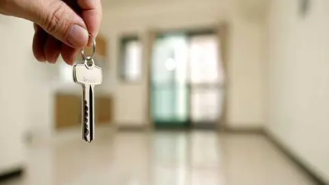 Apartment key in man hand in closeup view as house rental concept